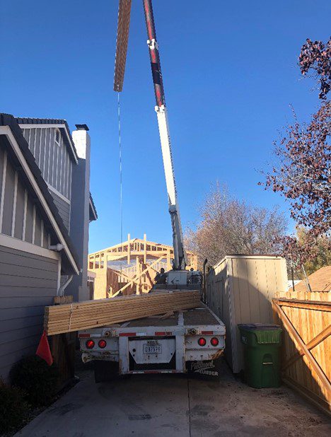 A crane is lifting lumber from the back of a truck.